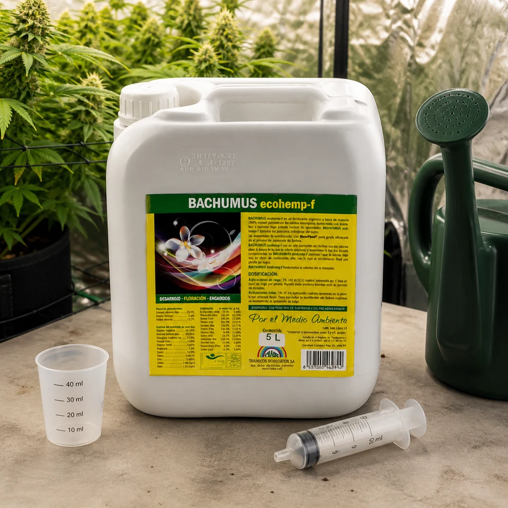 Garrafa de Bachumus Ecohemp Floración junto a un vaso medidor y una jeringa, con una regadera y plantas al fondo.