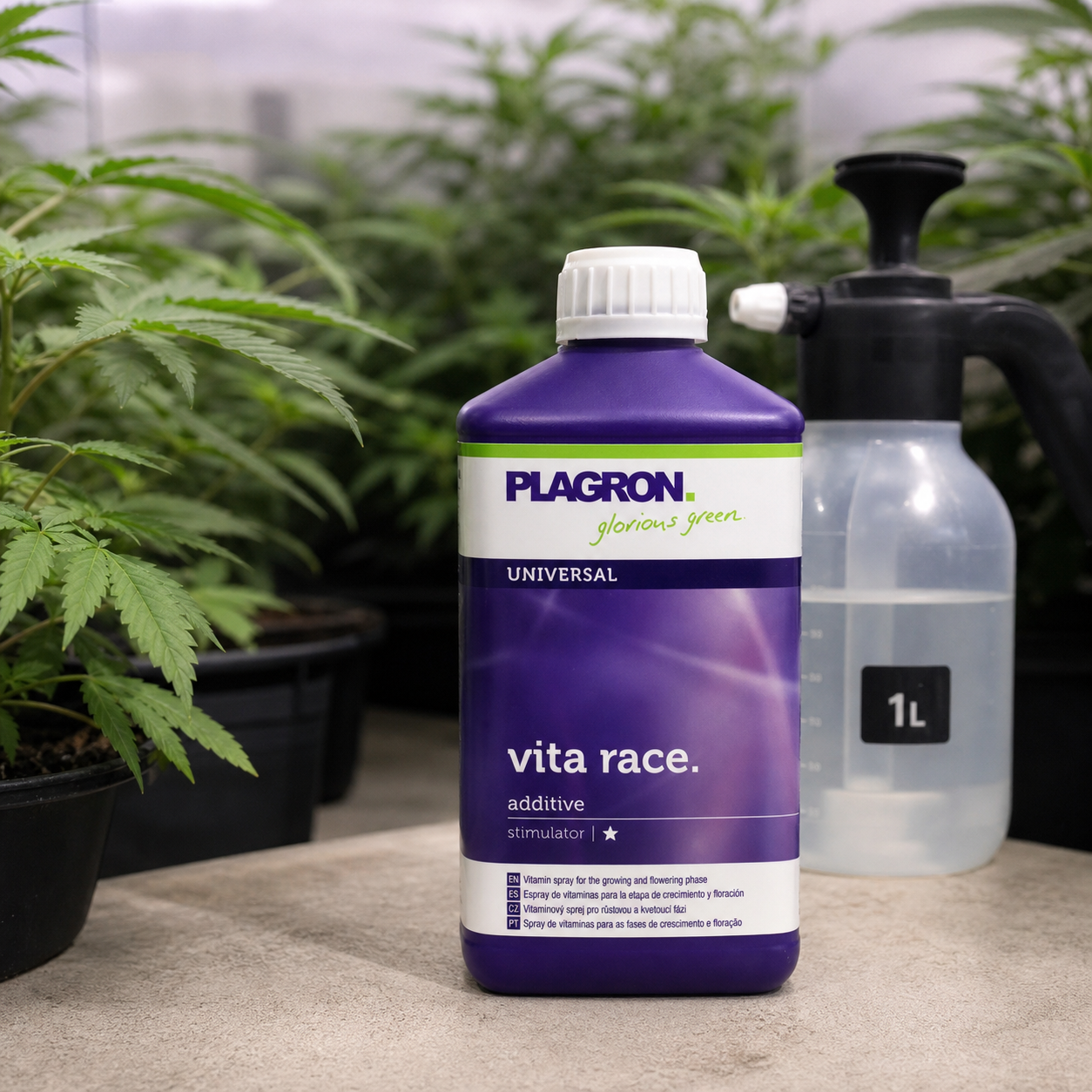 Botella morada de Plagron Vita Race con tapón blanco junto a un pulverizador de 1 L, con plantas de cannabis al fondo.