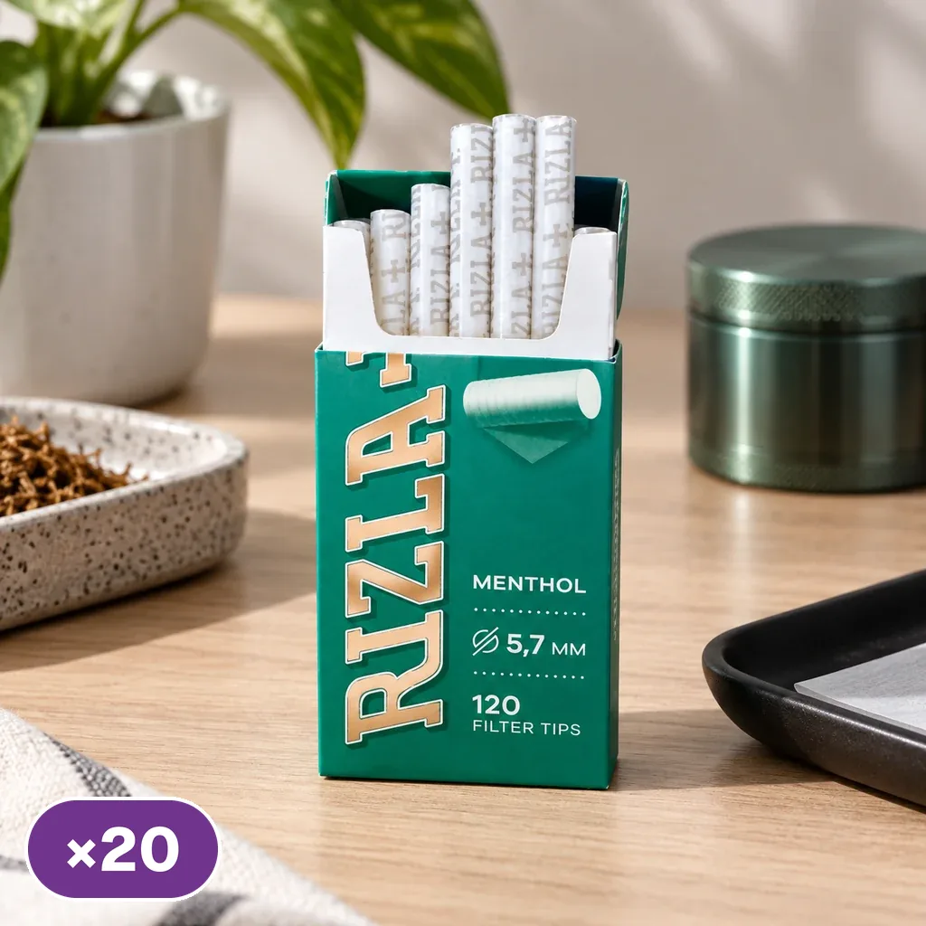Caja verde abierta de filtros Rizla Menthol con varias unidades visibles, sobre una mesa junto a un triturador y una bandeja.
