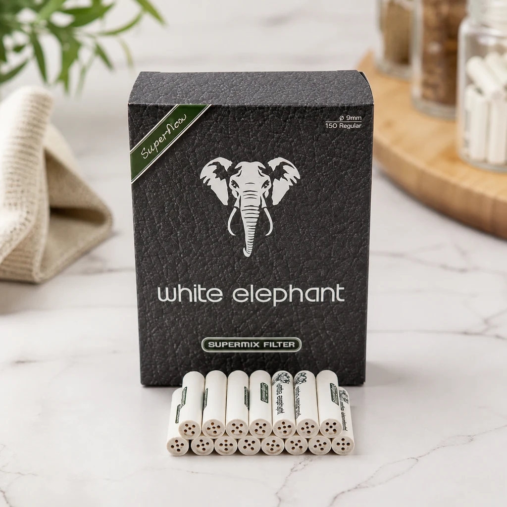 Caja negra White Elephant Supermix con un elefante blanco y varios filtros cilíndricos delante, sobre una superficie clara. Caja negra White Elephant Supermix con un elefante blanco y varios filtros cilíndricos delante, sobre una superficie clara.