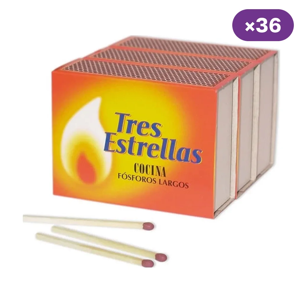 Cajas de fósforos Tres Estrellas apiladas, con etiqueta naranja y amarilla y varios fósforos de cabeza rojiza delante.