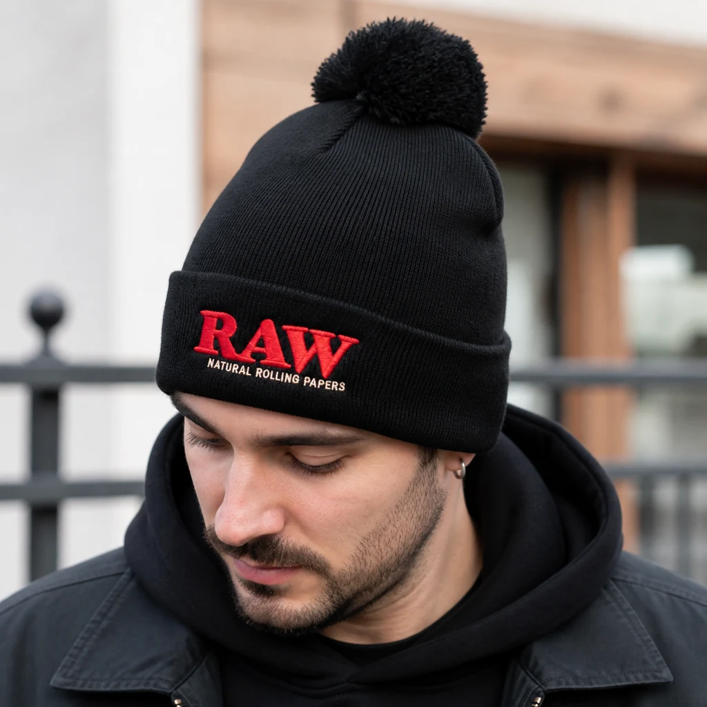 Escena generada de un hombre con gorro negro RAW Black Pom Pom, con pompón y logotipo rojo bordado en la vuelta frontal.