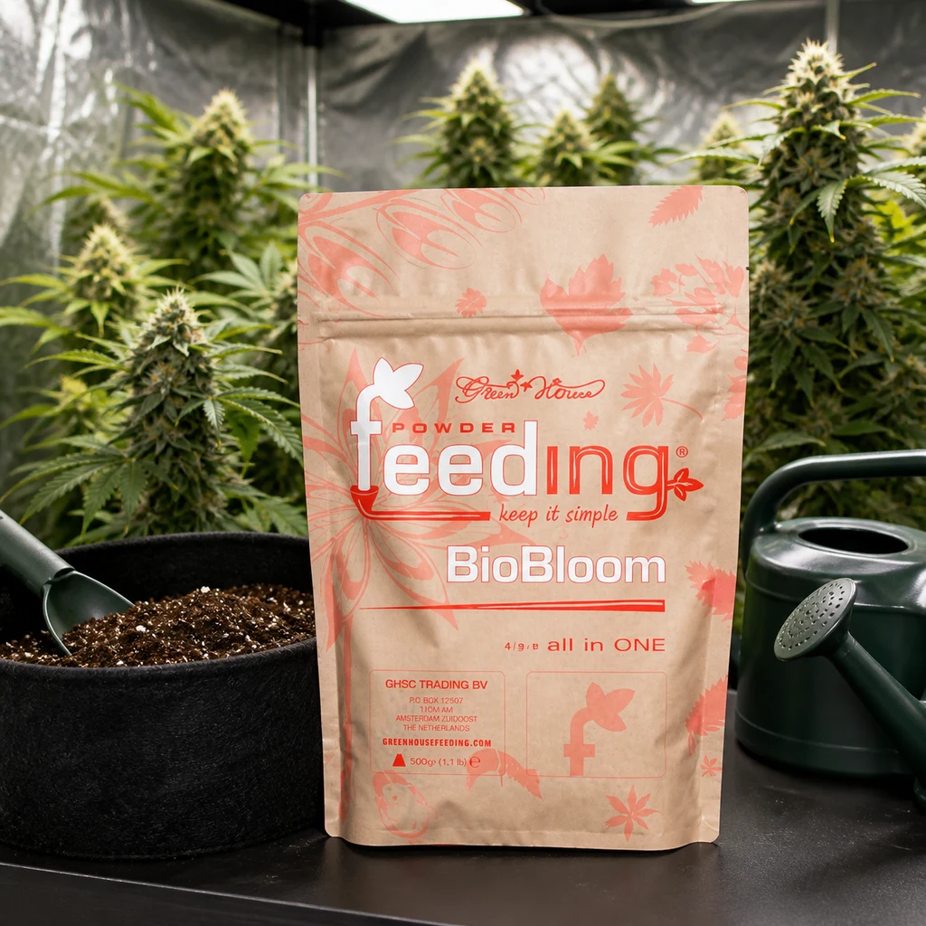 Bolsa de Green House Powder Feeding Bio Bloom junto a una maceta con sustrato y una regadera, con plantas en flor al fondo en una escena generada.