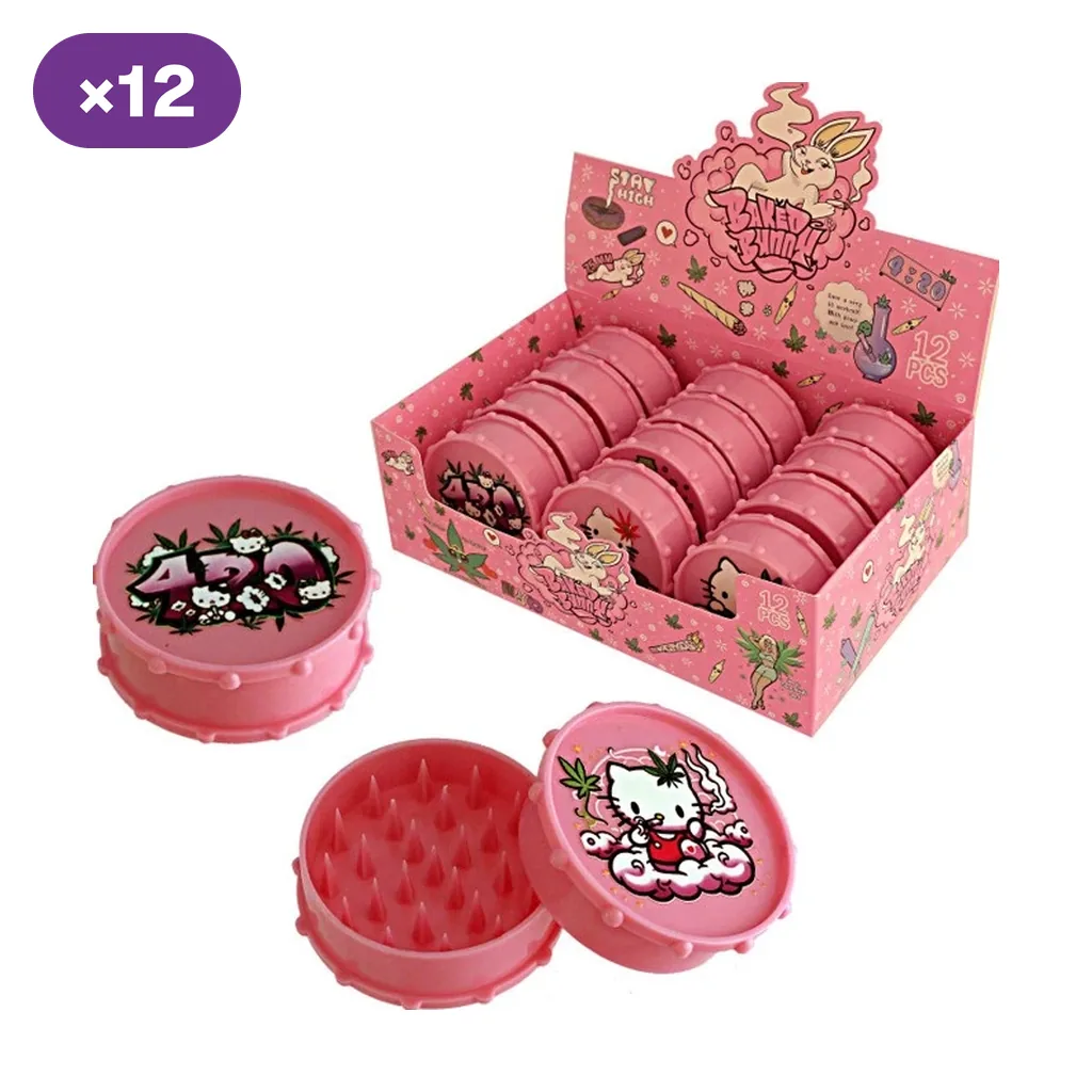 Grinders rosas con tapas de dibujos en una caja expositora; delante se muestran modelos cerrados y uno abierto con dientes puntiagudos.