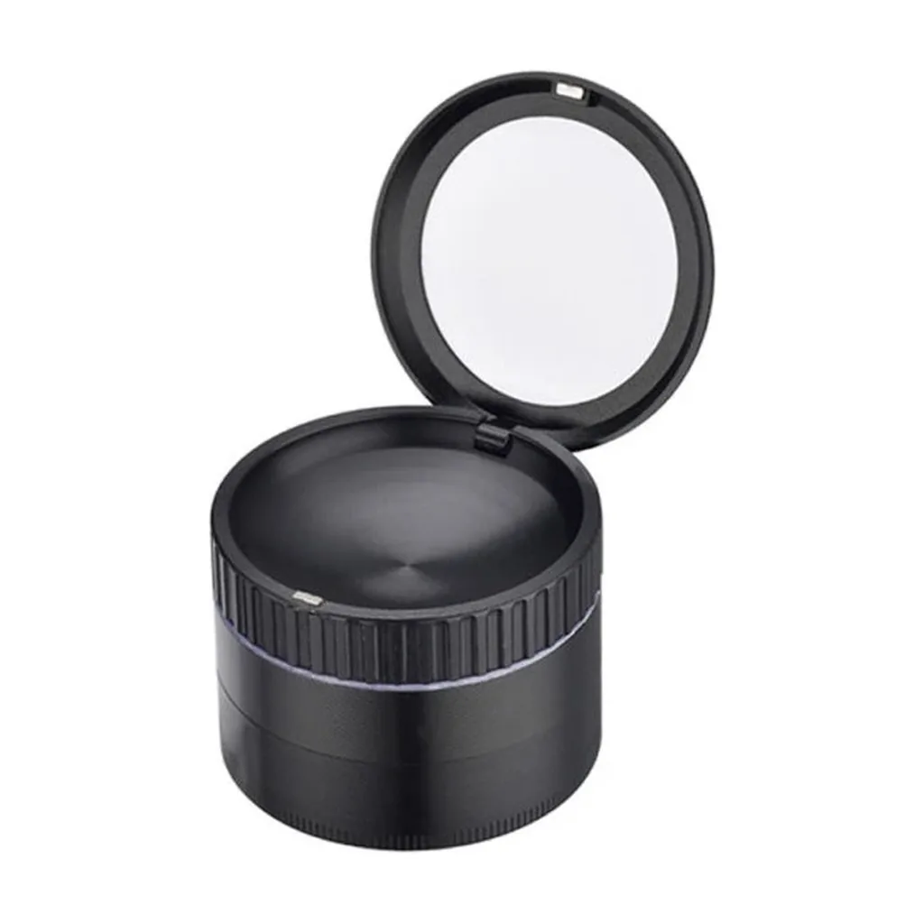 Grinder negro cilíndrico con borde estriado y tapa con lupa abierta, visto en ángulo sobre fondo blanco.