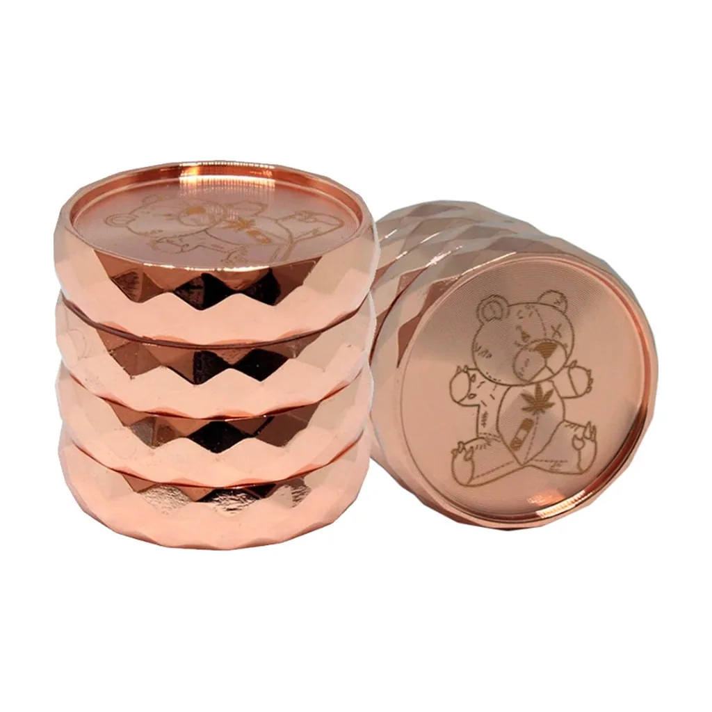 Grinder Teddy Montana en oro rosa, con cuerpo de varias secciones, bordes facetados y un oso grabado en la tapa, mostrado de pie y tumbado.