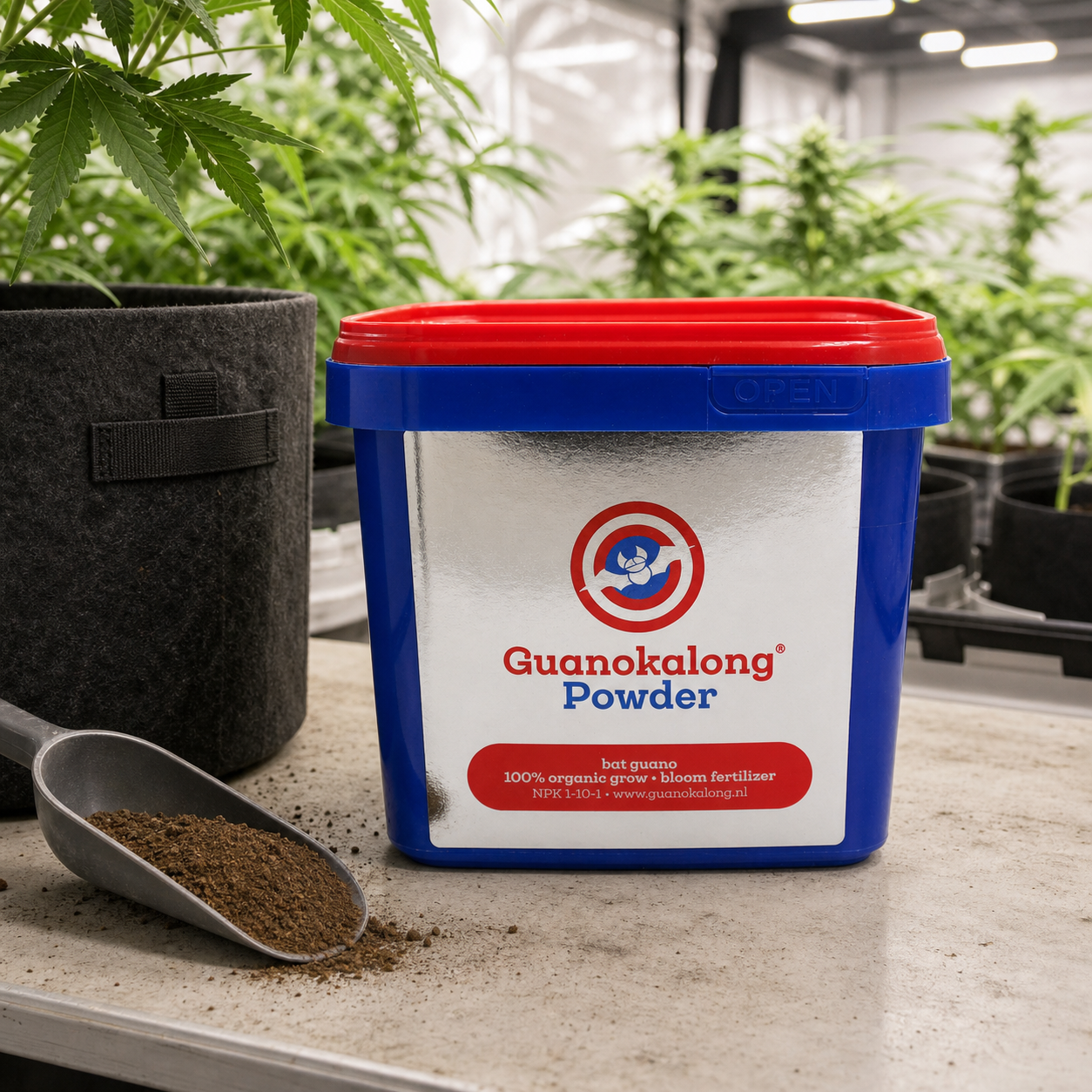 Cubo azul de Guanokalong en polvo con tapa roja, junto a una pala con abono y una maceta de tela en un cultivo interior.