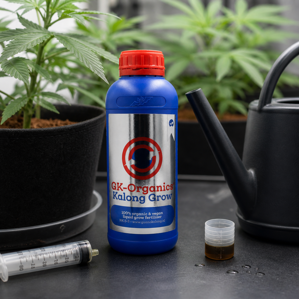 Botella azul de Kalong Grow con tapón rojo, junto a un dosificador con líquido, una jeringa y una regadera entre plantas en macetas.