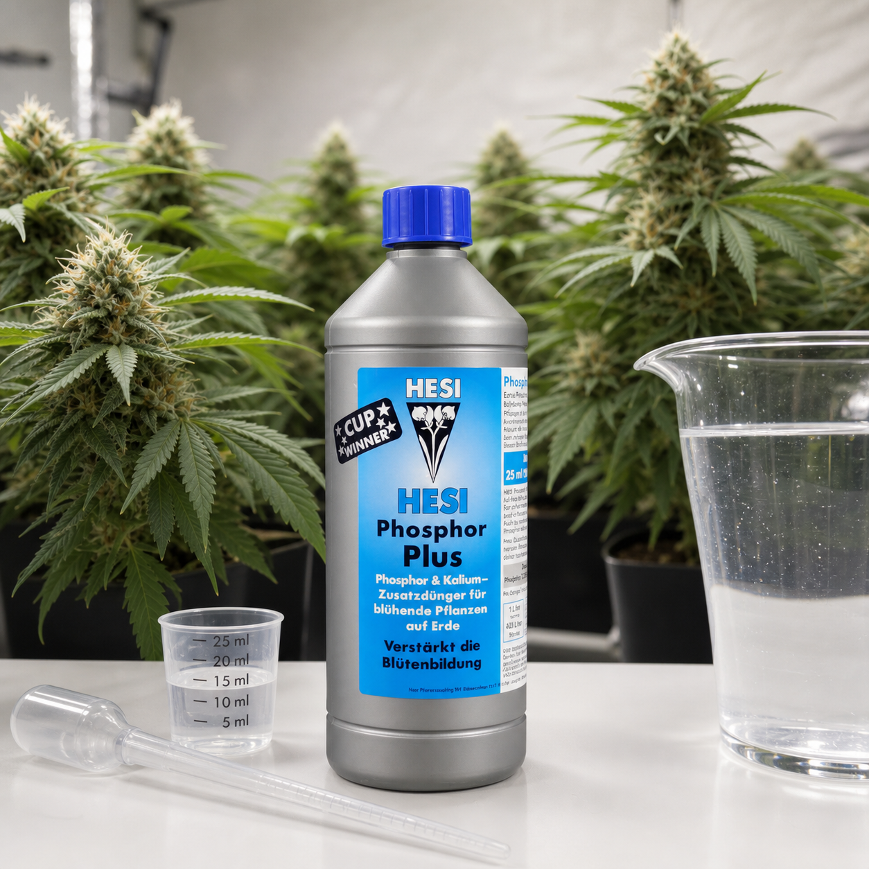 Botella de HESI Phosphorus Plus con tapón azul, junto a un vaso medidor, una pipeta y una jarra, con plantas al fondo. Botella de HESI Phosphorus Plus con tapón azul, junto a un vaso medidor, una pipeta y una jarra, con plantas al fondo.
