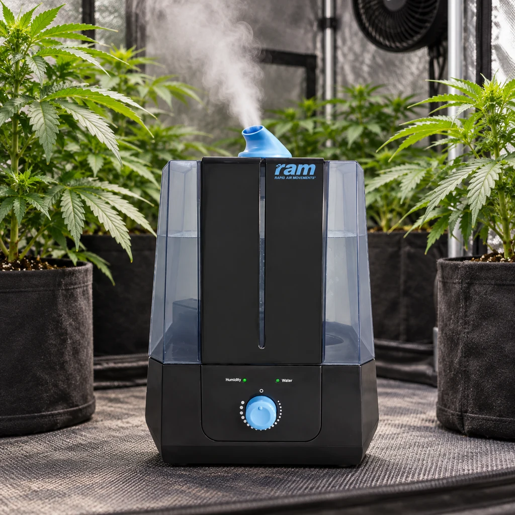 Humidificador RAM negro con depósitos translúcidos y mando azul, representado emitiendo niebla entre plantas en un armario de cultivo.