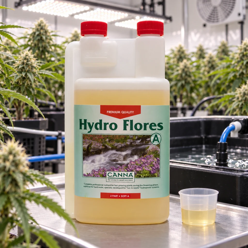 Envase de Canna Hydro Flores A con tapones rojos y líquido amarillo, junto a un vaso dosificador en un cultivo interior.