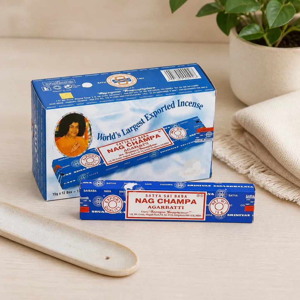 Caja y estuche azul de incienso Satya Nag Champa Agarbatti sobre una mesa clara, junto a un incensario alargado vacío.