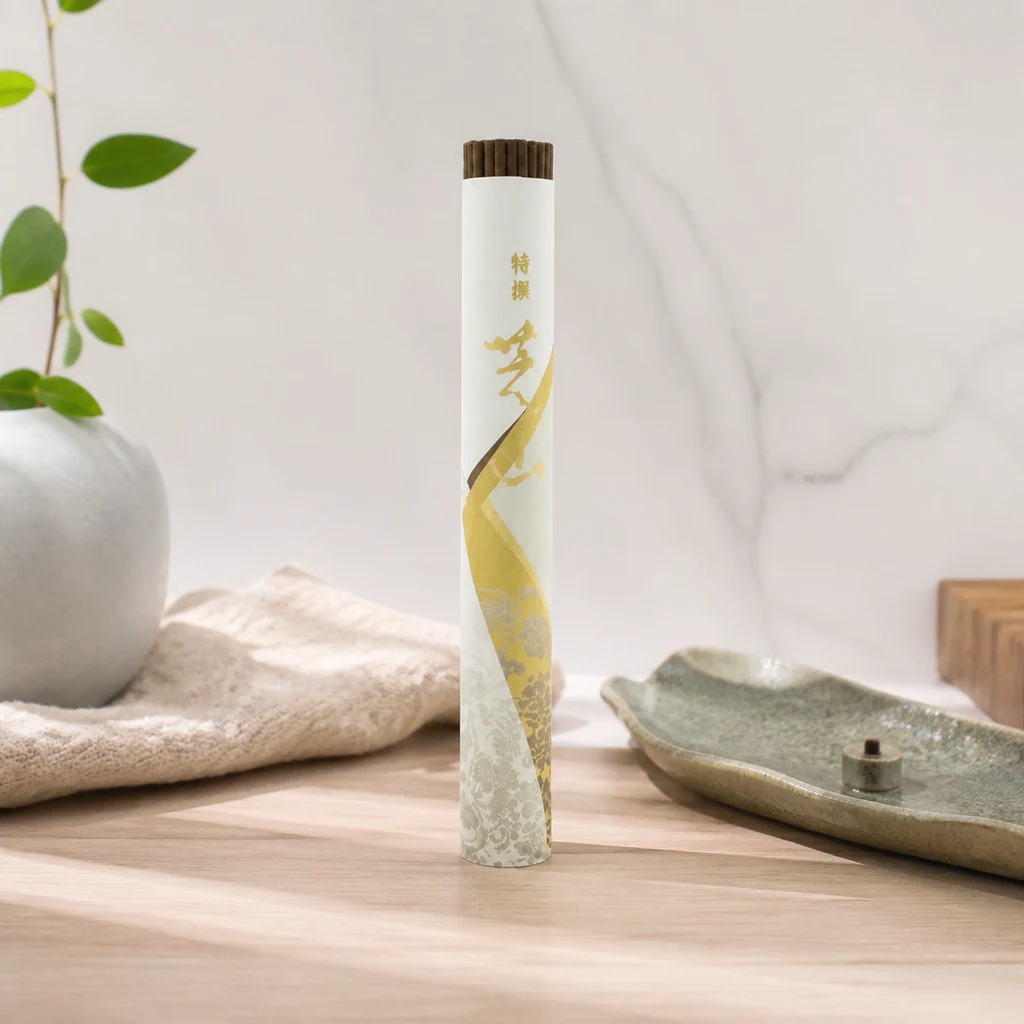Tubo de incienso Tokusen Shibayama con varillas asomando y decoración dorada, junto a una bandeja portaincienso sobre una mesa.
