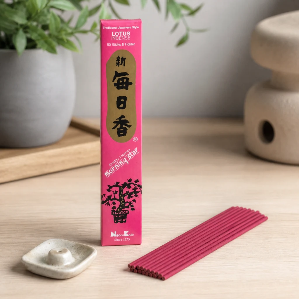 Caja rosa de incienso Morning Star Loto de Nippon Kodo, junto a varias varillas rosas y un pequeño soporte claro sobre una mesa. Caja rosa de incienso Morning Star Loto de Nippon Kodo, junto a varias varillas rosas y un pequeño soporte claro sobre una mesa.