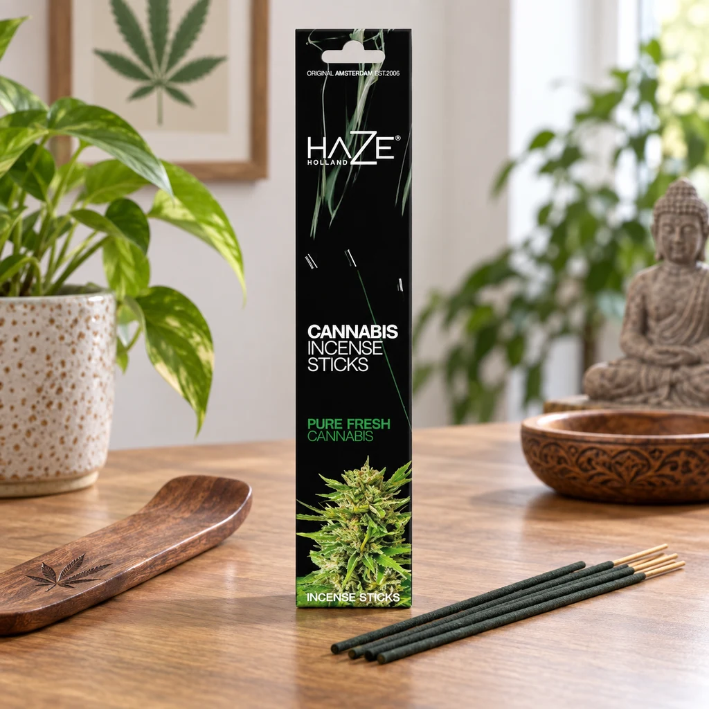 Caja negra de incienso Haze Pure Fresh Cannabis junto a varias varillas sobre una mesa de madera y un soporte alargado. Caja negra de incienso Haze Pure Fresh Cannabis junto a varias varillas sobre una mesa de madera y un soporte alargado.