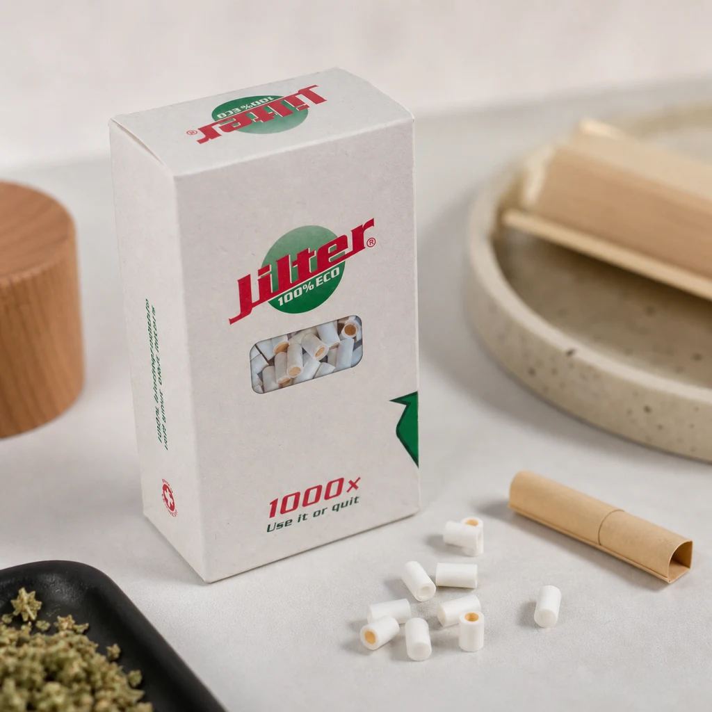 Caja de filtros Jilter con ventana frontal, varios filtros blancos sobre la mesa y papel de liar marrón a su lado.