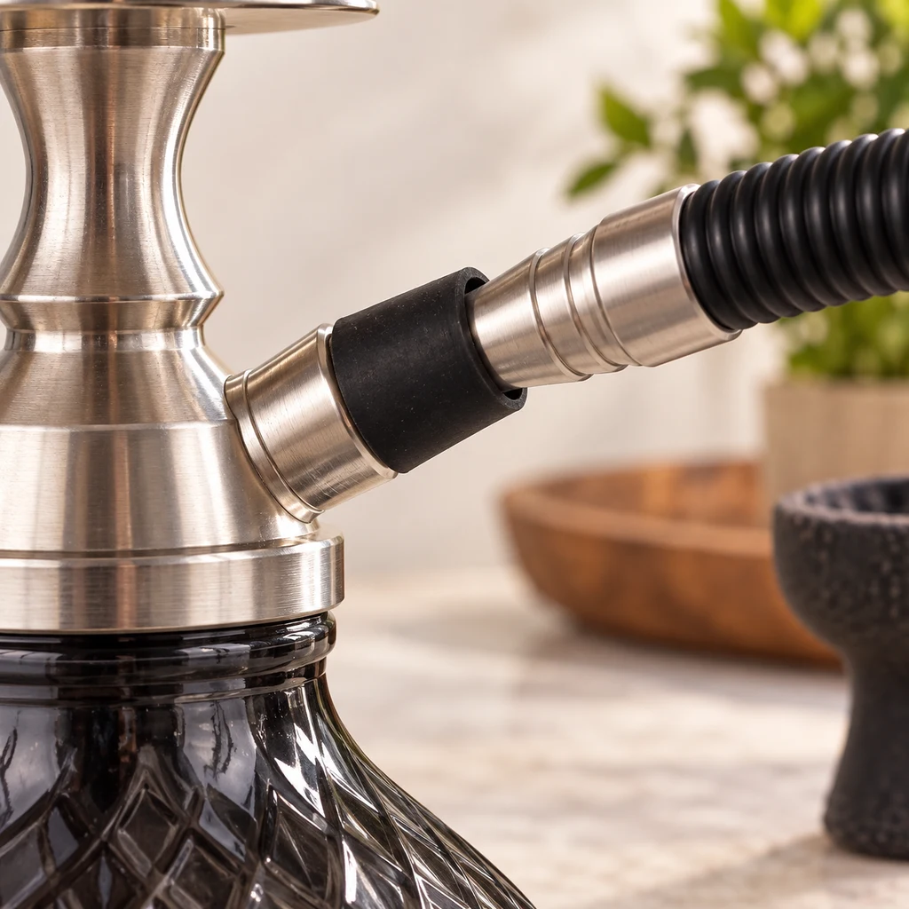 Detalle de una junta negra en la conexión entre el cuerpo metálico de una shisha y su manguera negra corrugada, sobre una base de vidrio oscuro. Detalle de una junta negra en la conexión entre el cuerpo metálico de una shisha y su manguera negra corrugada, sobre una base de vidrio oscuro.