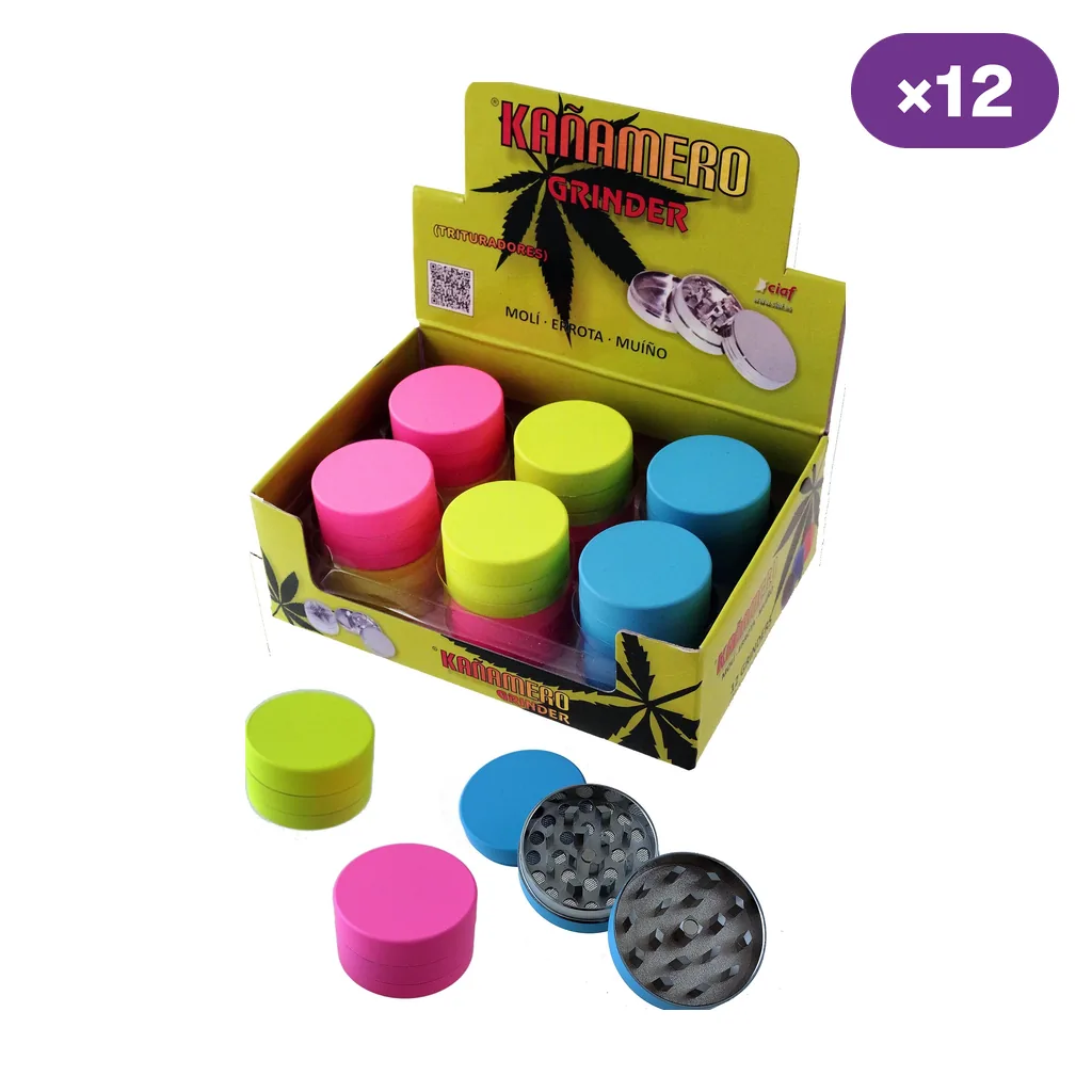 Expositor de grinders Kañamero rosas, verdes y azules, con varias unidades fuera de la caja y un grinder abierto que muestra sus dientes.