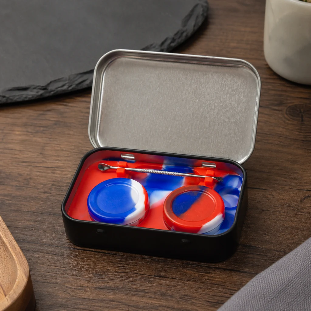 Estuche negro abierto del kit dab sobre una mesa, con interior rojo, azul y blanco, recipientes redondos y una herramienta metálica.