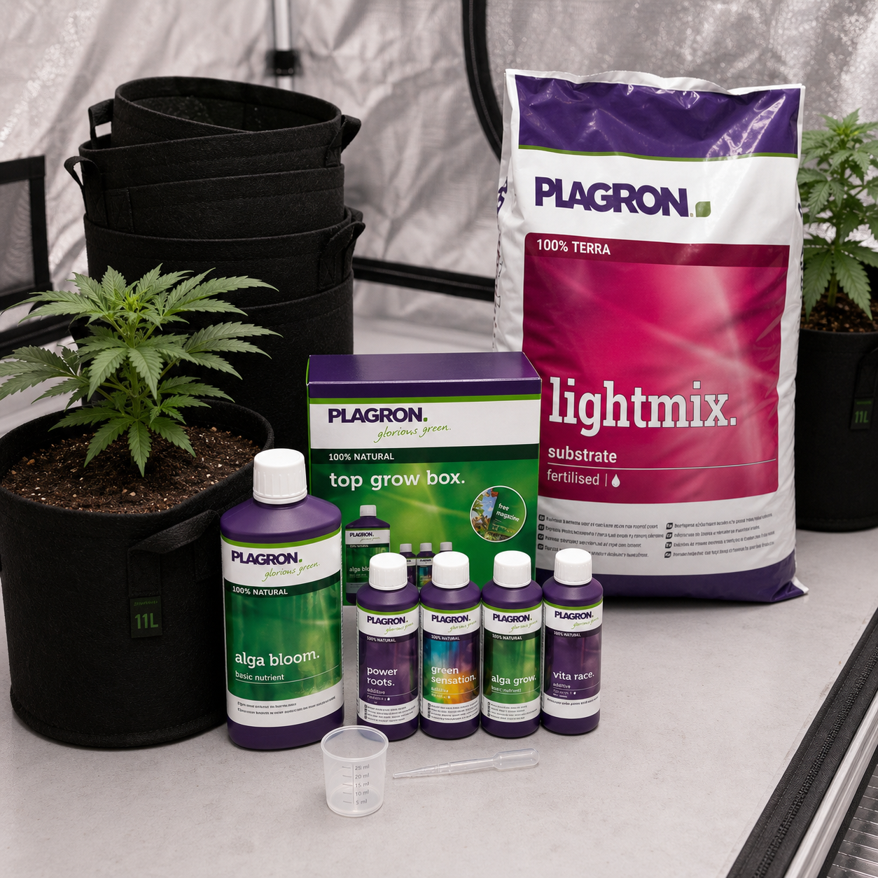 Fertilizantes Plagron con caja Top Grow Box, saco Lightmix y utensilios de medida junto a plantas y macetas textiles en un armario de cultivo. Fertilizantes Plagron con caja Top Grow Box, saco Lightmix y utensilios de medida junto a plantas y macetas textiles en un armario de cultivo.