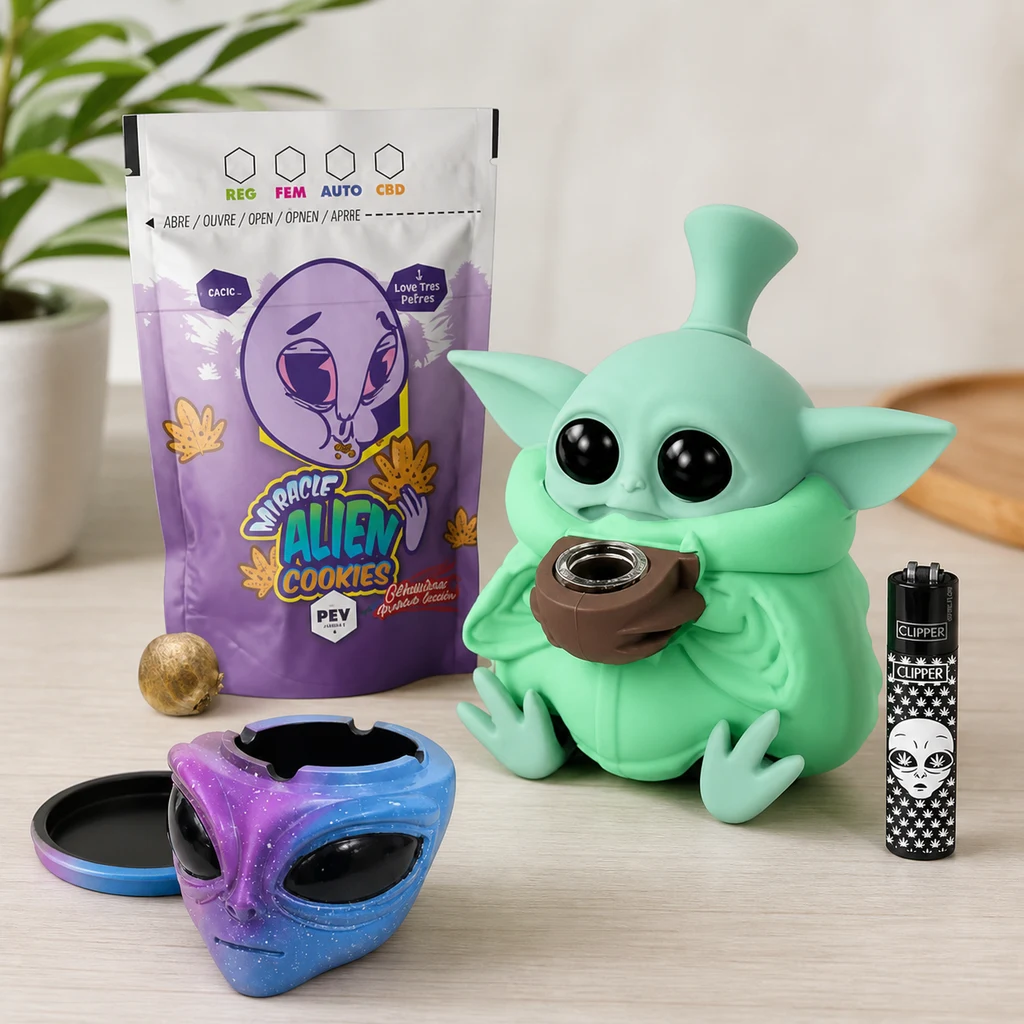 Kit Alien para Fumar sobre una mesa, con figura verde de grandes ojos, accesorio con cara alienígena, mechero y bolsa morada.