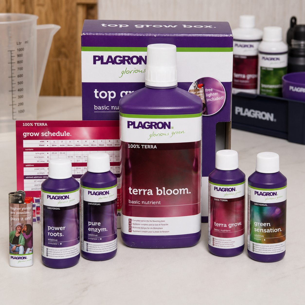 Plagron Top Grow Box Soil con envases de nutrientes y aditivos de distintos tamaños, tabla de cultivo y caja al fondo. Plagron Top Grow Box Soil con envases de nutrientes y aditivos de distintos tamaños, tabla de cultivo y caja al fondo.