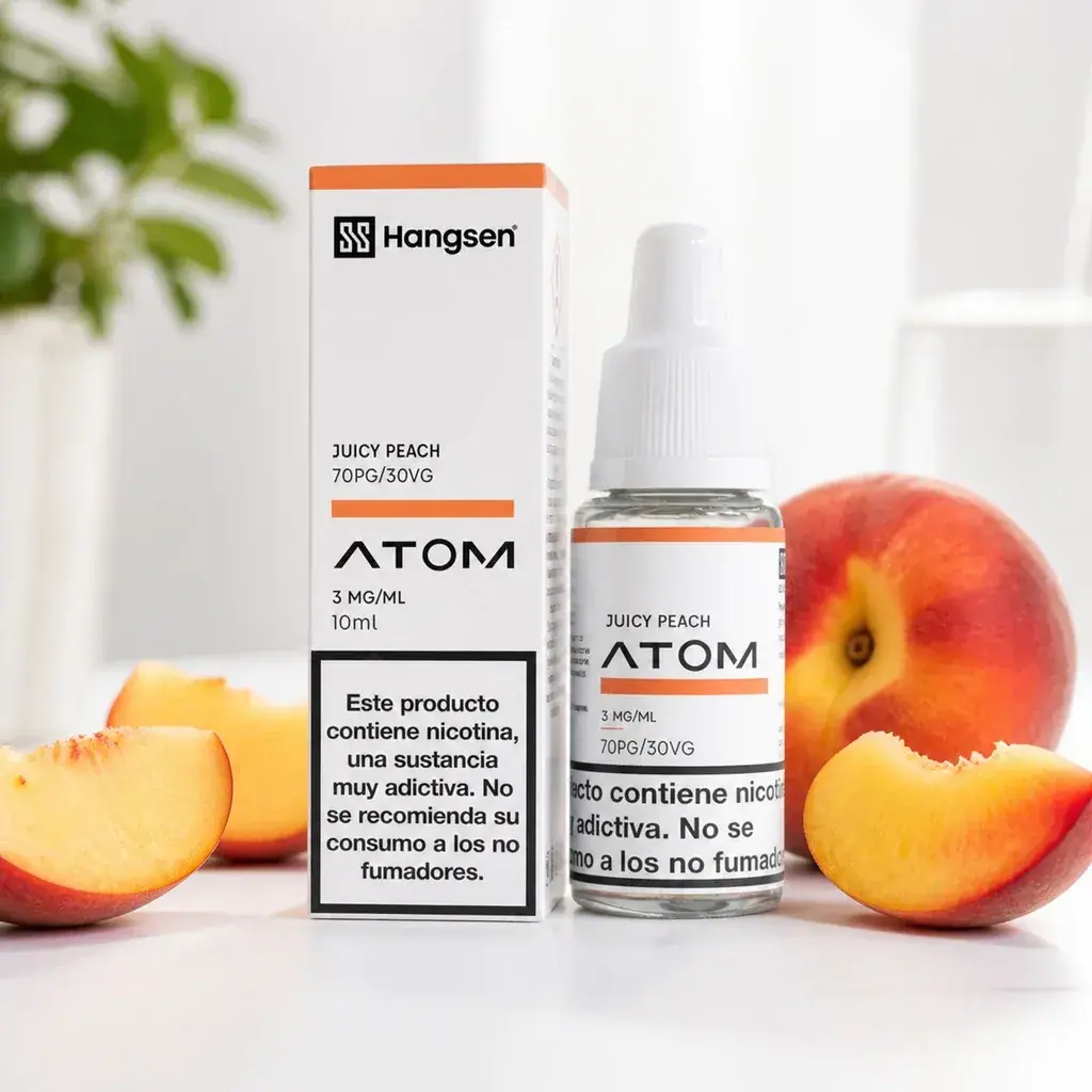 Caja y frasco de Hangsen ATOM Juicy Peach, con etiquetas de 3 mg/ml y advertencia de nicotina, rodeados de melocotones enteros y cortados.