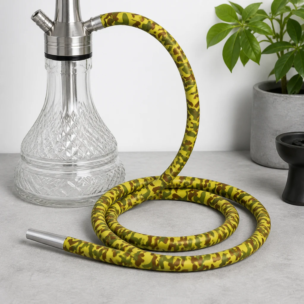 Manguera de cachimba con estampado de camuflaje amarillo, verde y marrón, enrollada junto a una base transparente y con boquilla plateada.