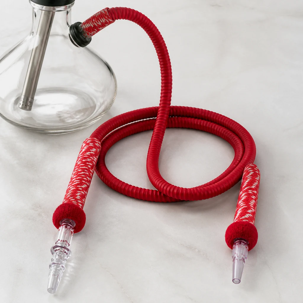 Tubo rojo de cachimba enrollado, con extremos decorados en blanco y boquillas transparentes, junto a una base de cristal.