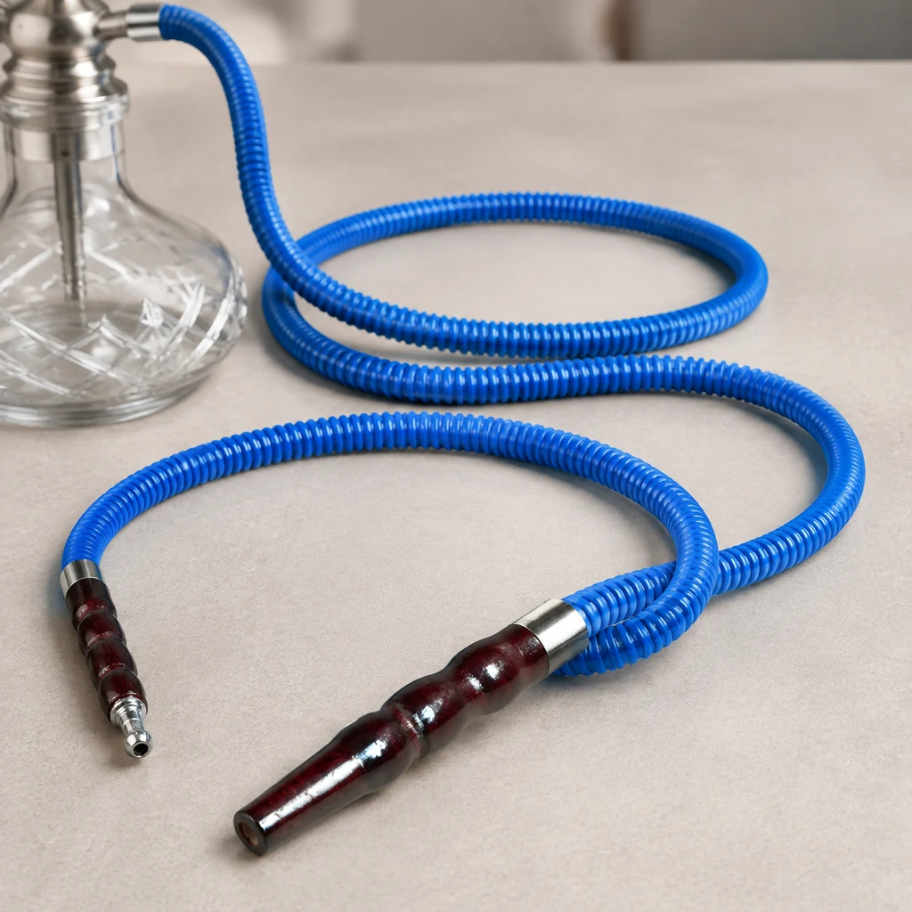 Manguera azul corrugada dispuesta en curvas, con boquilla oscura y conexiones plateadas junto a una cachimba parcialmente visible. Manguera azul corrugada dispuesta en curvas, con boquilla oscura y conexiones plateadas junto a una cachimba parcialmente visible.