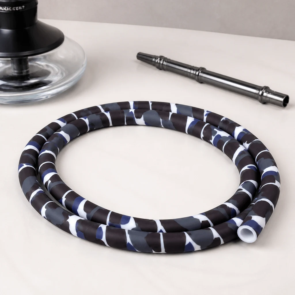 Manguera para cachimba enrollada con estampado de camuflaje negro, gris, azul y blanco, junto a una boquilla metálica y parte de una cachimba.