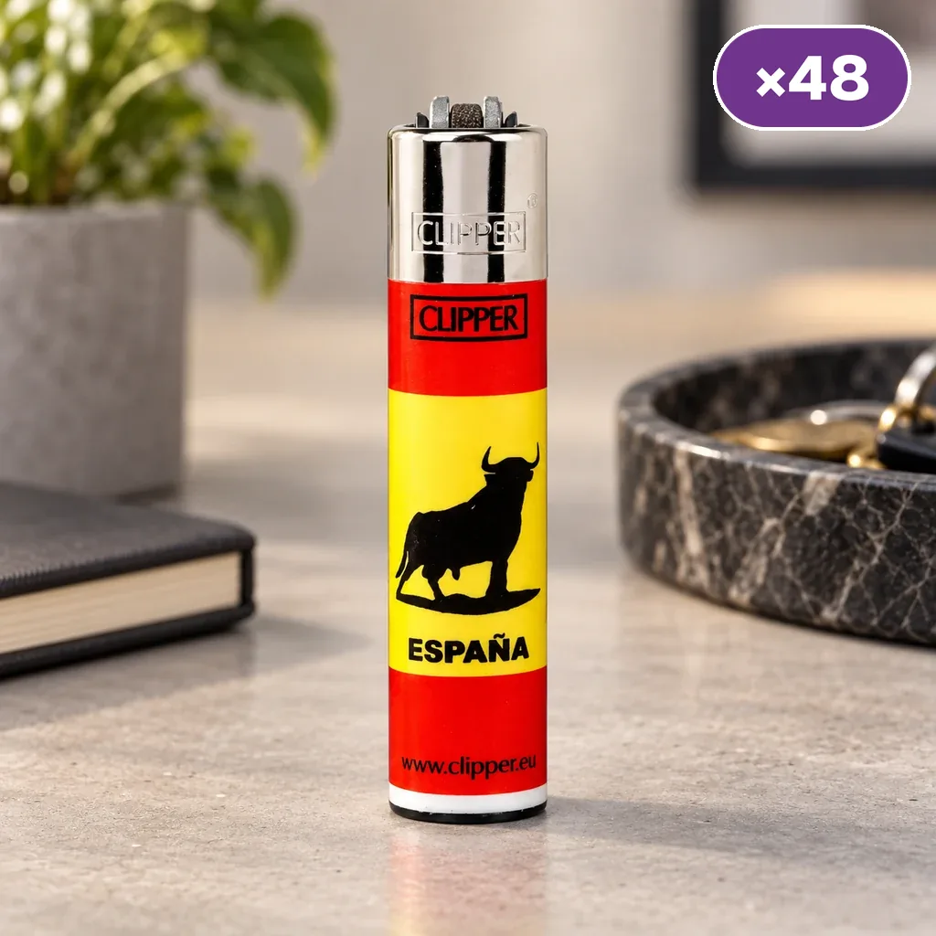 Encendedor Clipper rojo y amarillo con silueta de toro y texto «España», de pie sobre una mesa, con distintivo ×48 en la esquina.