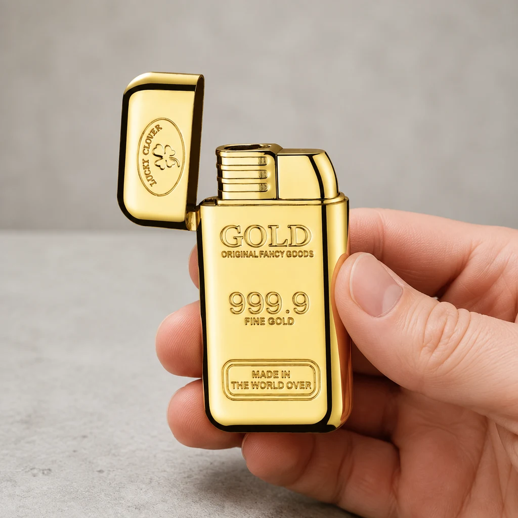 Una mano sostiene un encendedor Jet Flame Goldbar dorado con la tapa abierta y las inscripciones GOLD y 999.9 en el frontal.