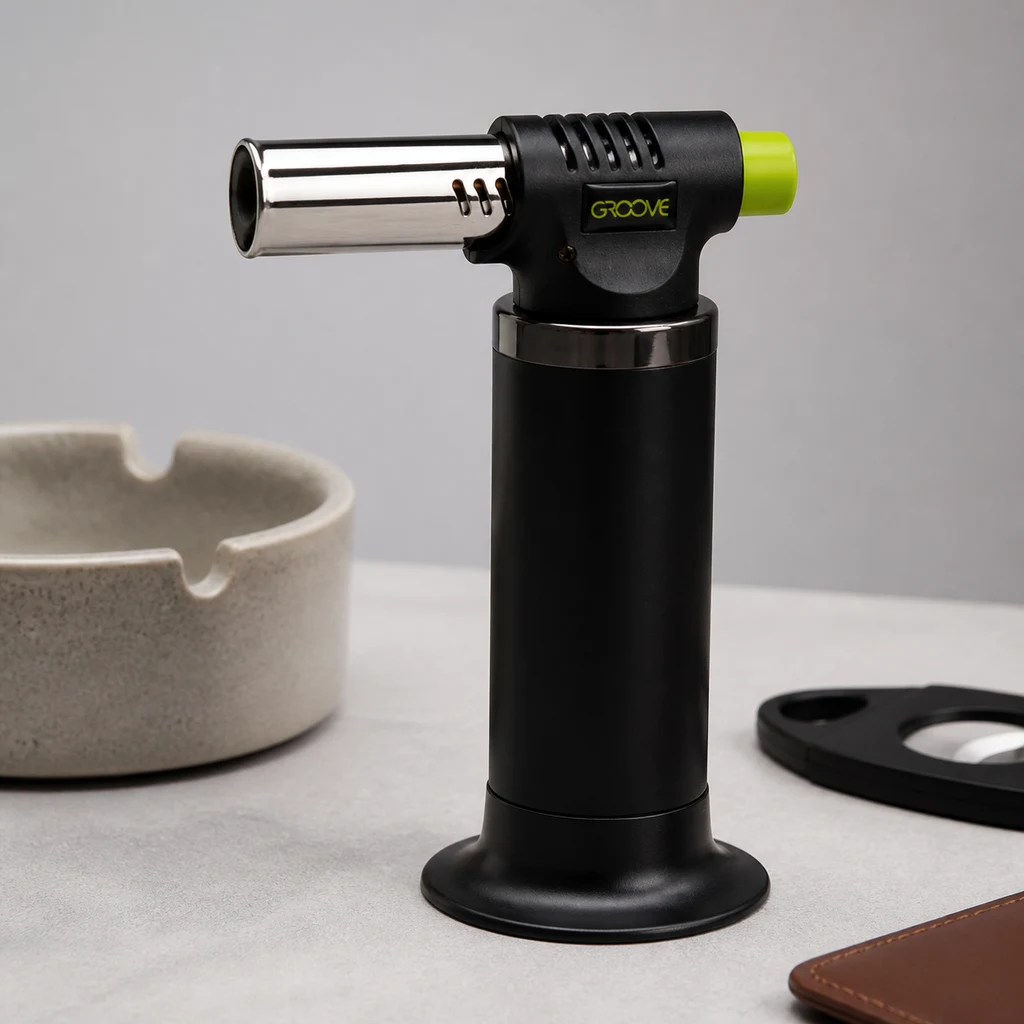 Mechero Torch Black Groove Spark de pie, con cuerpo negro, boquilla plateada y botón verde, junto a un cenicero.