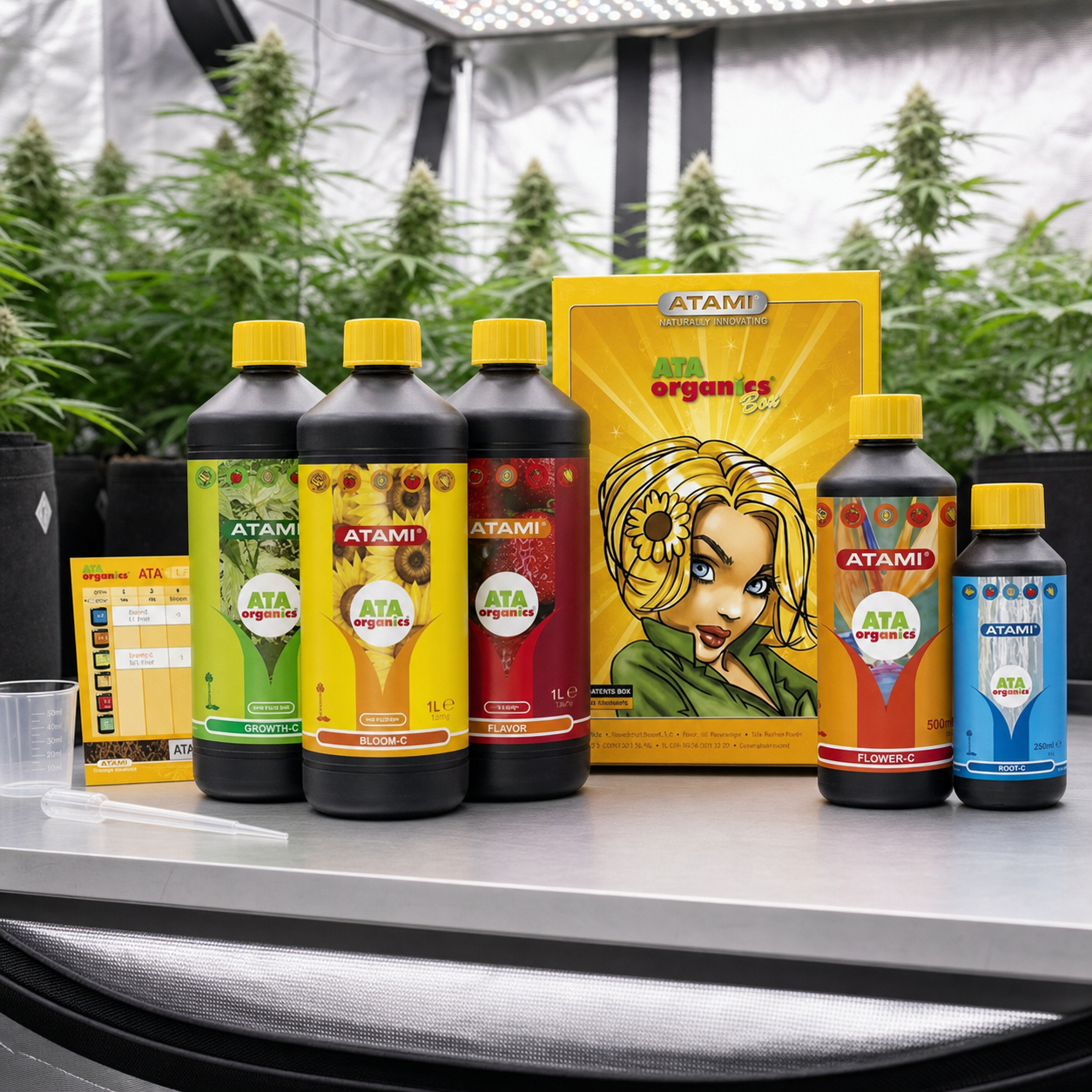 Cinco botellas ATA Organics de Atami con tapones amarillos junto a su caja, sobre una mesa ante plantas de cannabis y un panel de luces.