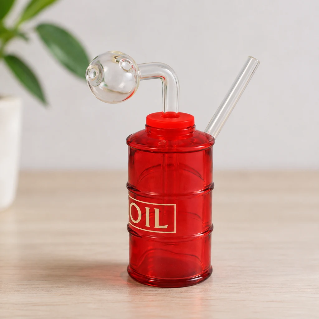 Mini bong rojo con forma de barril y texto «OIL», boquilla inclinada y cazoleta esférica transparente, sobre una mesa de madera.