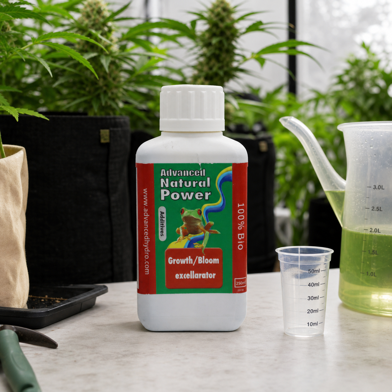 Botella Advanced Natural Power Growth/Bloom junto a un vaso dosificador y una jarra con líquido verdoso, con plantas de cannabis al fondo.