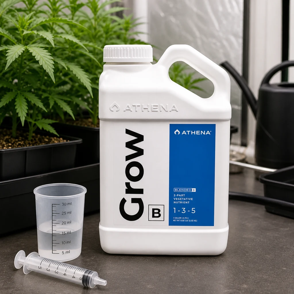 Garrafa blanca de Athena Grow B con etiqueta azul y fórmula 1-3-5, junto a un vaso graduado y una jeringa, con plantas al fondo.
