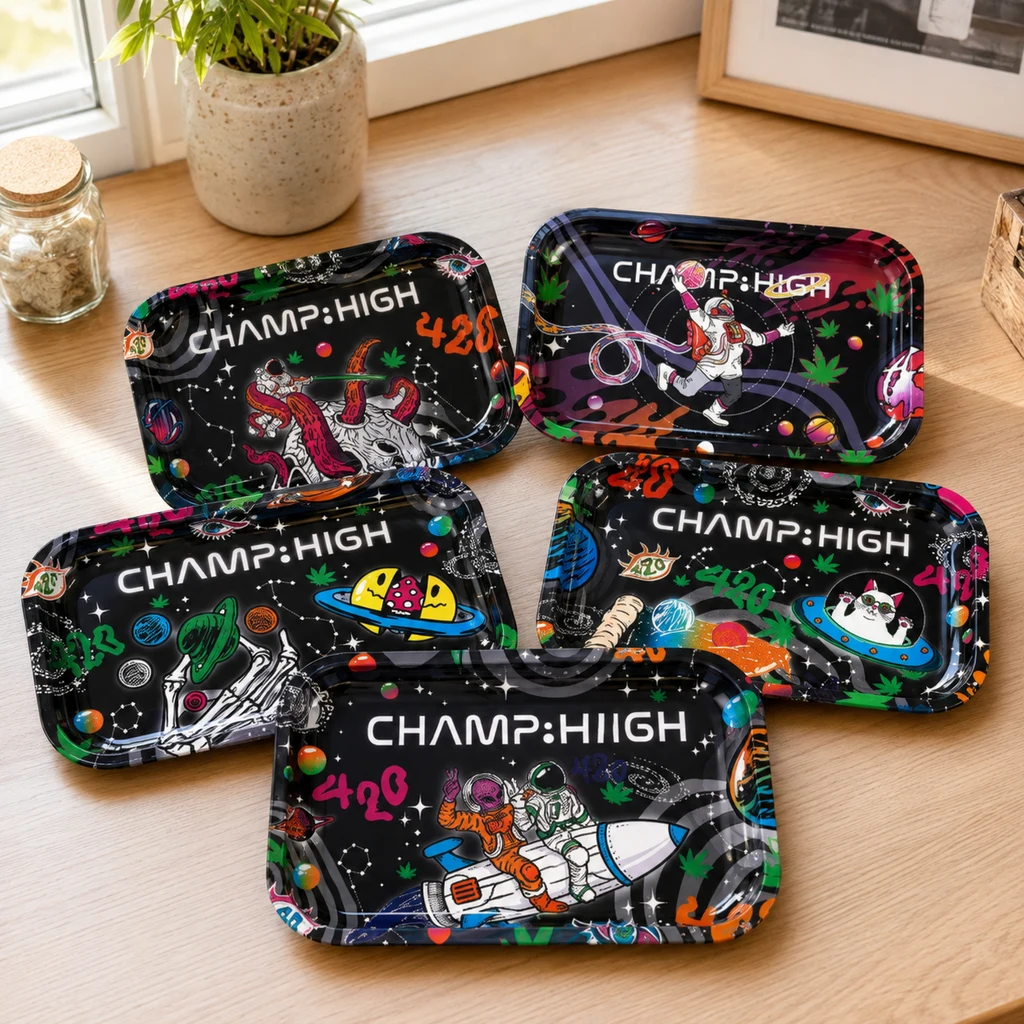Selección de bandejas Champ High negras con distintos diseños espaciales de colores, astronautas y hojas de cannabis sobre una mesa.