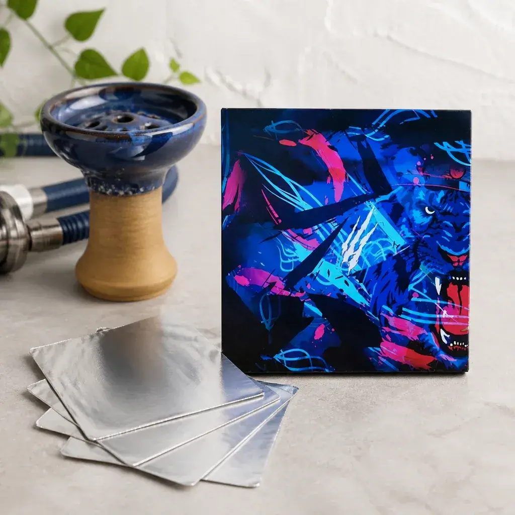 Láminas cuadradas de aluminio apiladas junto a un envase con ilustración de felino azul y rosa y una cazoleta de cachimba.