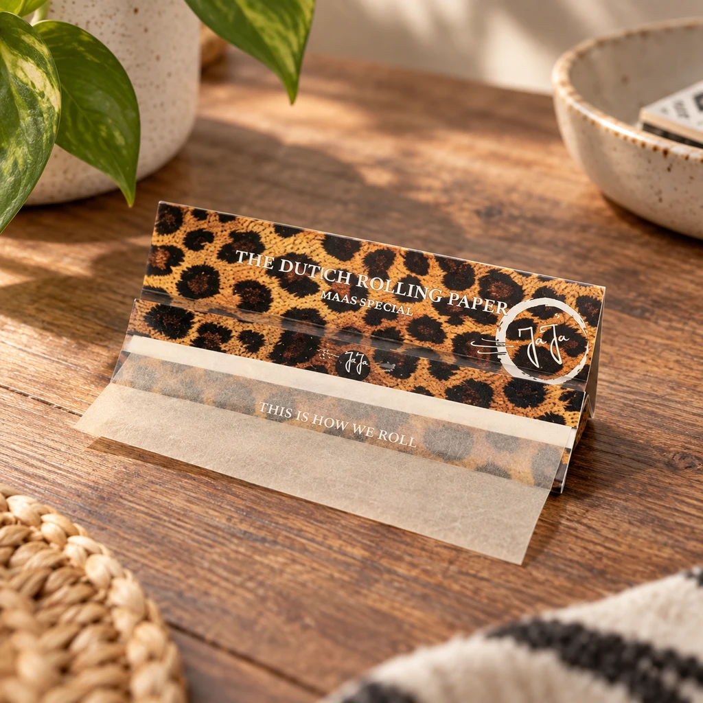 Librillo abierto de papel de liar Jaja Safari con estampado de leopardo y una hoja desplegada sobre una mesa de madera.