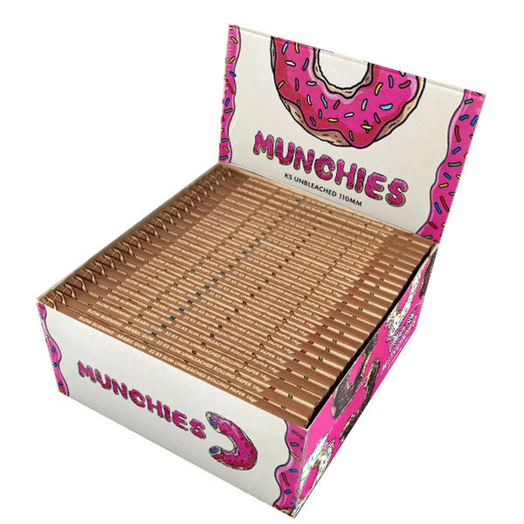 Expositor abierto de papel de liar Munchies King Size Slim sin blanquear, con librillos marrones y dibujos de donuts con glaseado rosa.