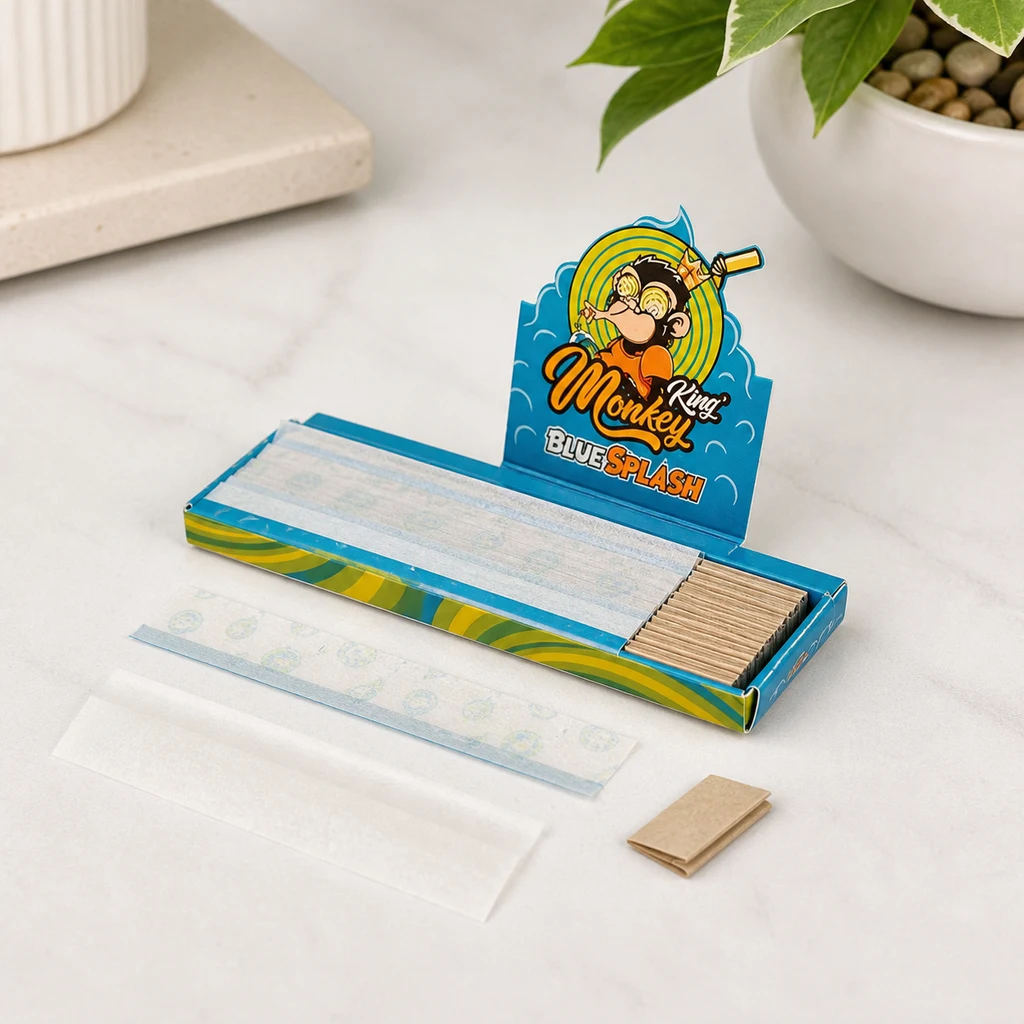 Estuche abierto de papel de liar Monkey King Blue Splash con filtros de cartón, papeles desplegados y filtros sueltos sobre una mesa.