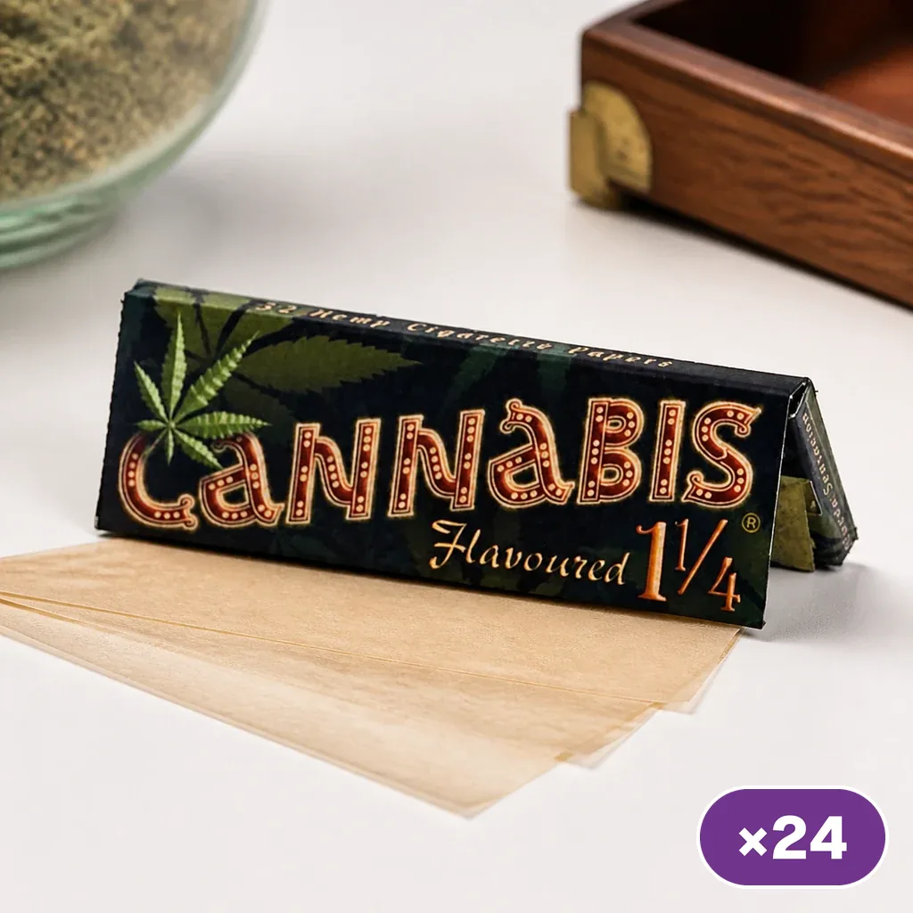 Librillo de papel de liar Cannabis Flavoured 1 1/4 con hojas marrones extendidas sobre la mesa y distintivo de 24 unidades.