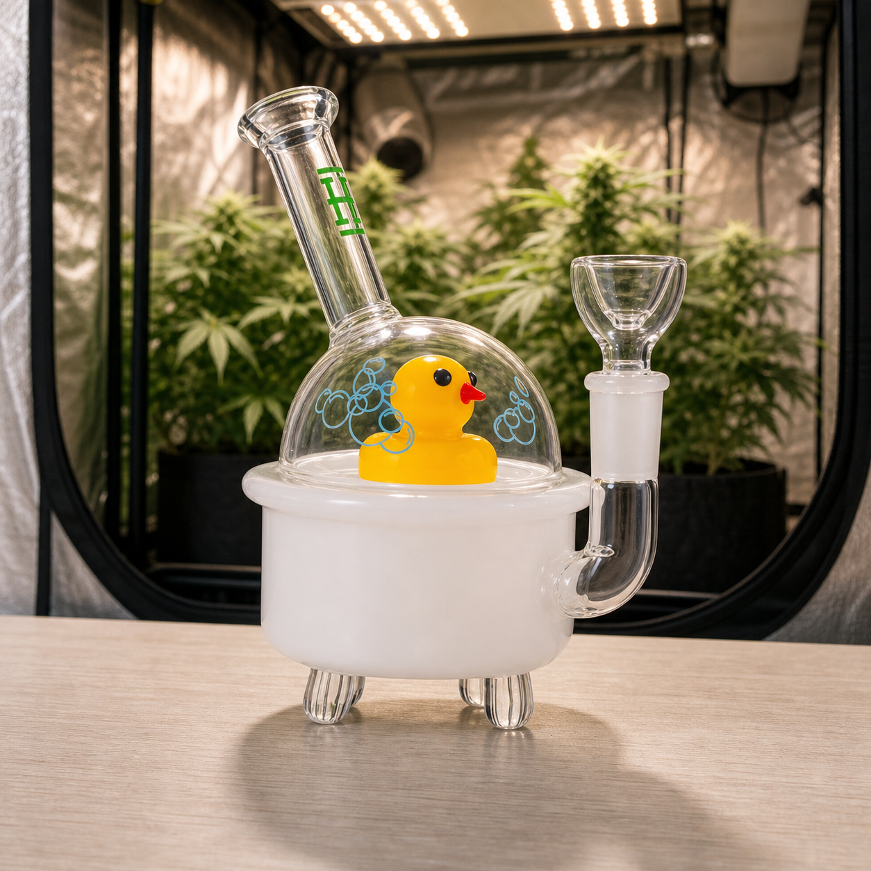 Ducky Bong Hemper con base blanca de bañera, patito amarillo bajo una cúpula transparente y tubo inclinado, ante un armario de cultivo.