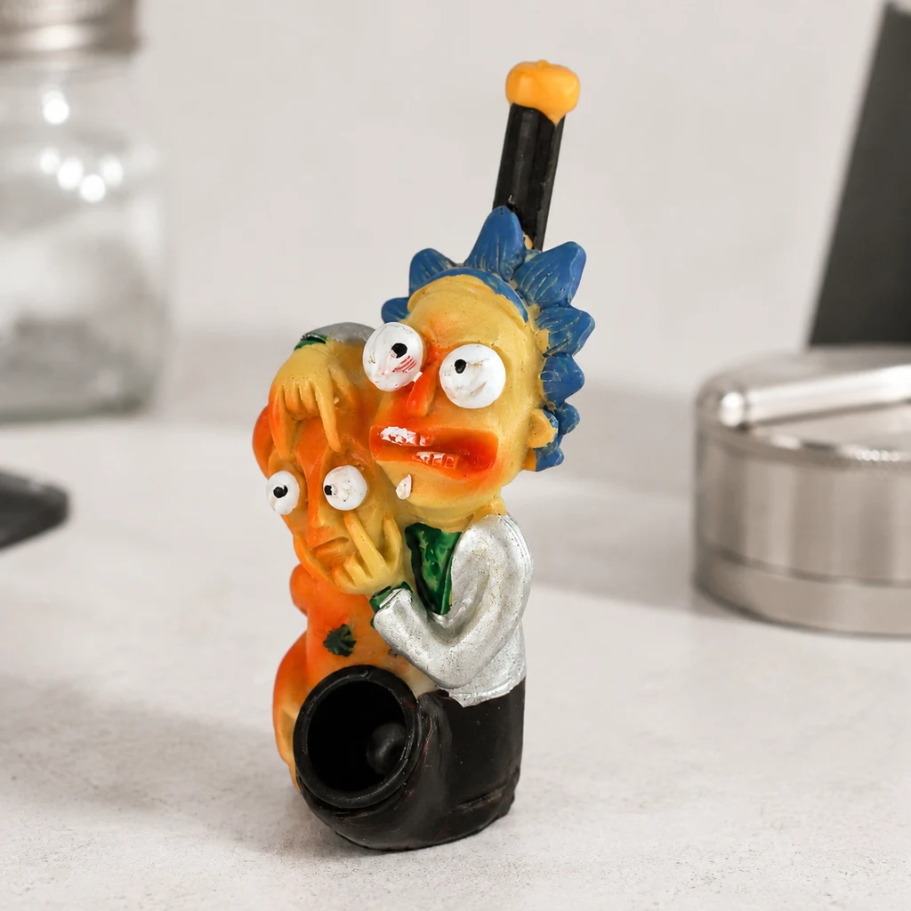 Pipa vertical con figuras de Rick y Morty abrazados, cazoleta negra frontal y boquilla elevada, sobre una encimera clara.