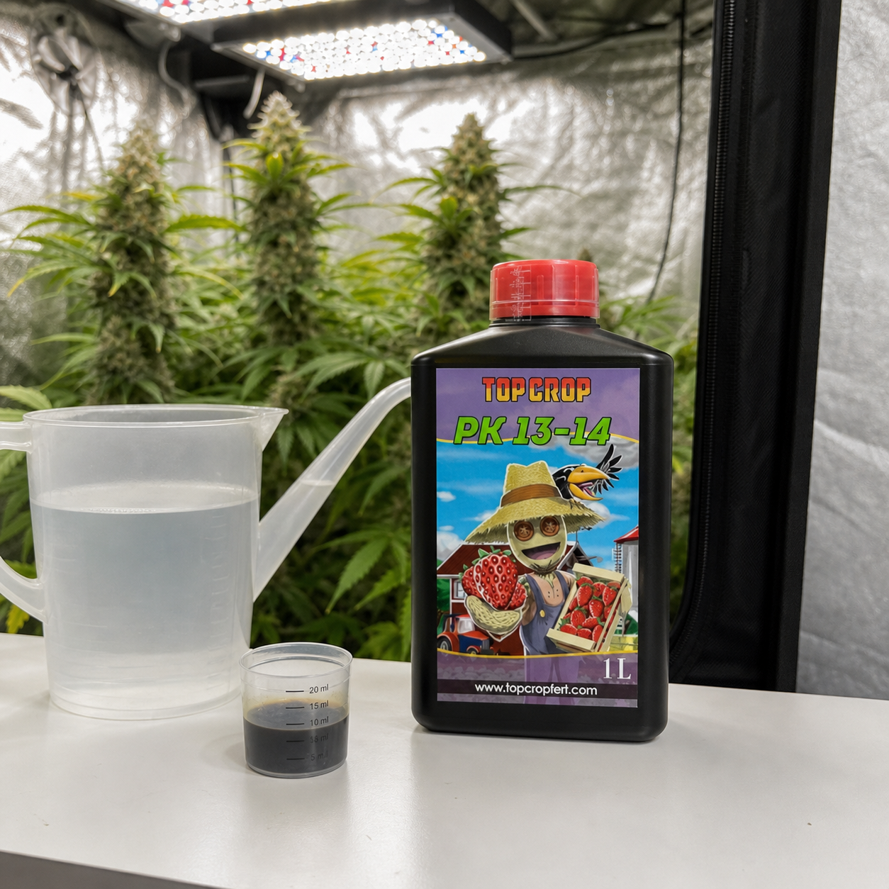 Botella de PK 13-14 Top Crop de 1 L junto a una jarra con agua y un vaso dosificador, con plantas al fondo de un armario de cultivo. Botella de PK 13-14 Top Crop de 1 L junto a una jarra con agua y un vaso dosificador, con plantas al fondo de un armario de cultivo.