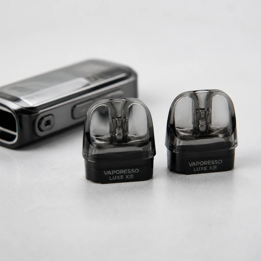 Pods Vaporesso Luxe XR con depósito transparente y base negra, en primer plano junto a un dispositivo desenfocado. Pods Vaporesso Luxe XR con depósito transparente y base negra, en primer plano junto a un dispositivo desenfocado.