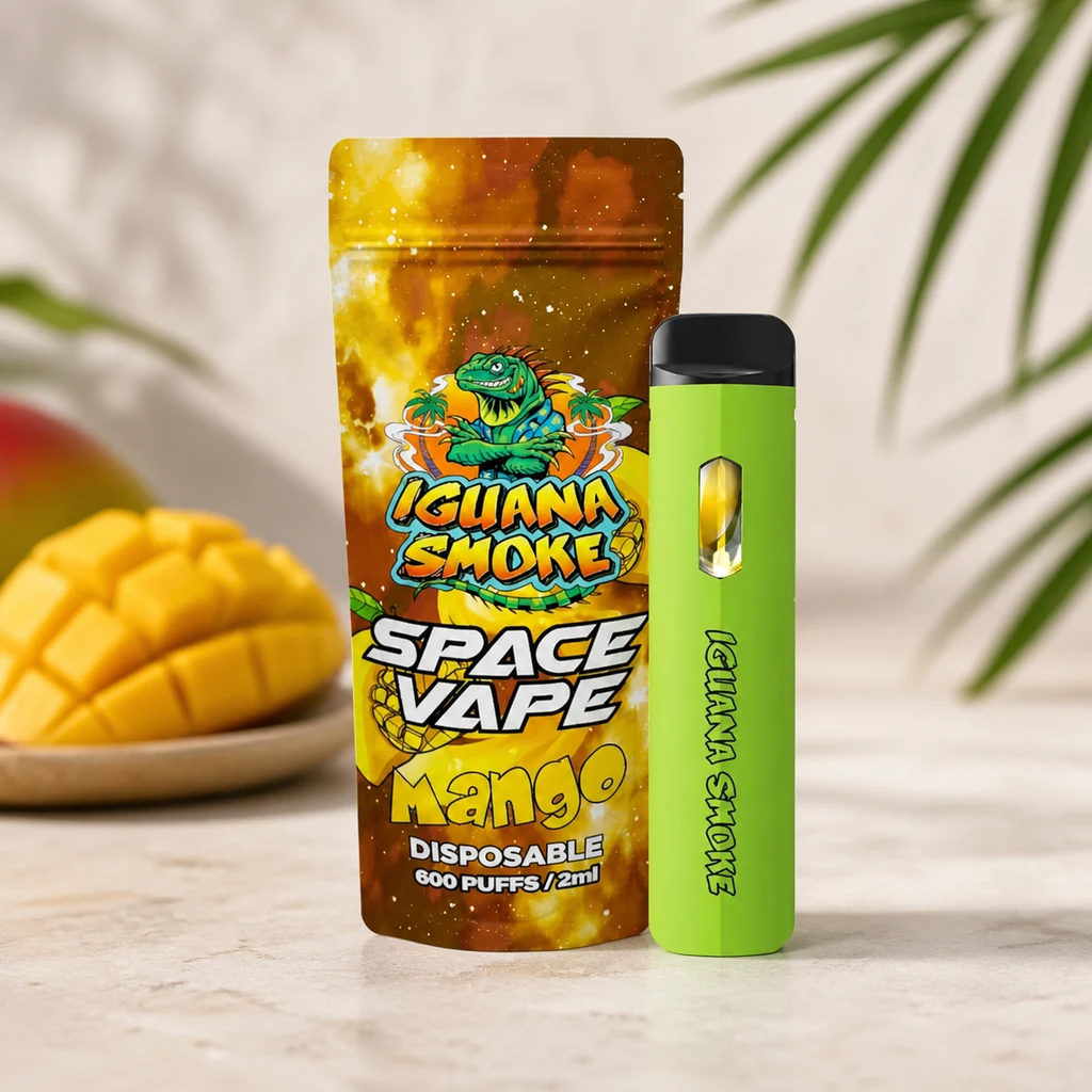 Vaper verde con boquilla negra junto a una bolsa Iguana Smoke Space Vape Mango, con mango cortado y hojas al fondo.
