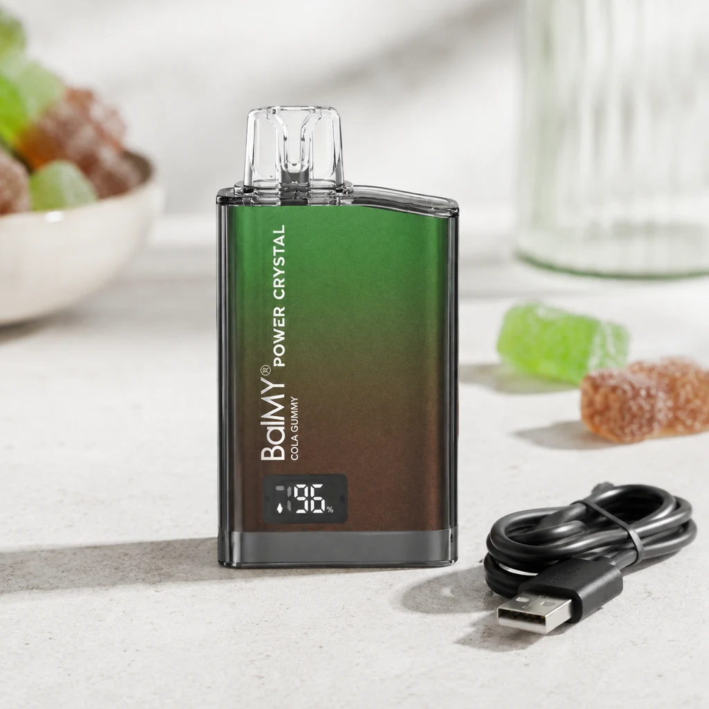Balmy Power Crystal Cola Gummy con cuerpo verde y marrón, boquilla transparente y pantalla, junto a un cable USB y golosinas.